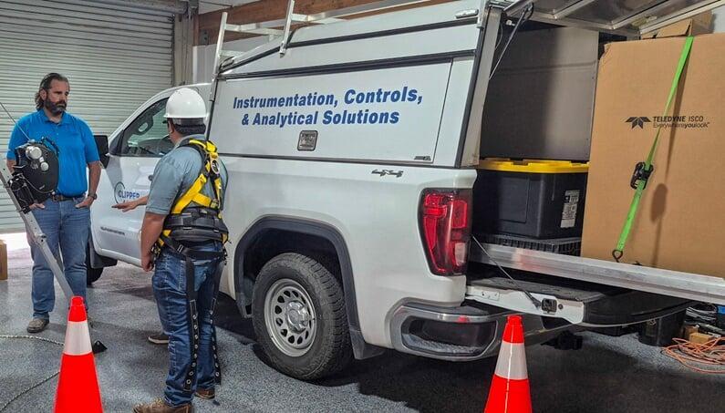 Field service technician next to a truck with a brand new ISCO water sampler in the truck bed