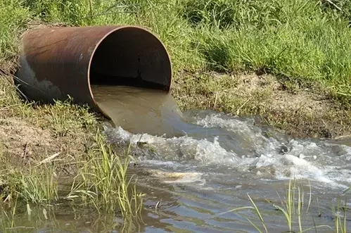 Wastewater flowing from an outfall pipe into an open channel where flow monitoring equipment may be used.